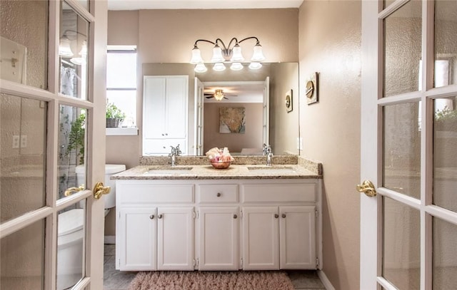 full bath with a ceiling fan, a sink, double vanity, and toilet