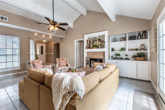 living area with visible vents, a ceiling fan, vaulted ceiling with beams, light tile patterned flooring, and a fireplace