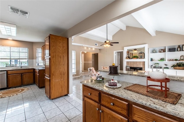 kitchen with a sink, open floor plan, vaulted ceiling with beams, visible vents, and brown cabinetry