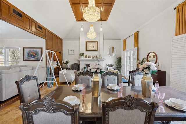 dining area featuring visible vents, a fireplace, ornamental molding, vaulted ceiling, and a chandelier