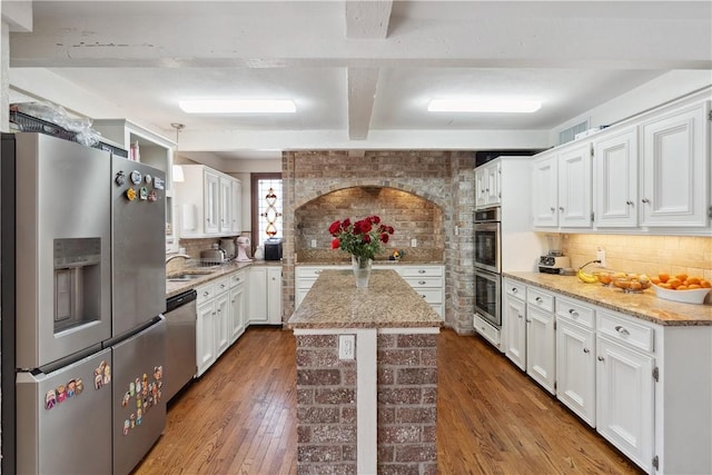 kitchen with stainless steel appliances, backsplash, beamed ceiling, and white cabinets