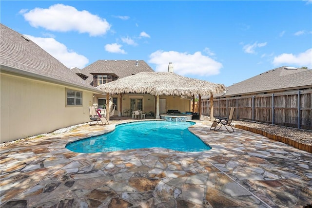 view of swimming pool with a patio, a pool with connected hot tub, and fence