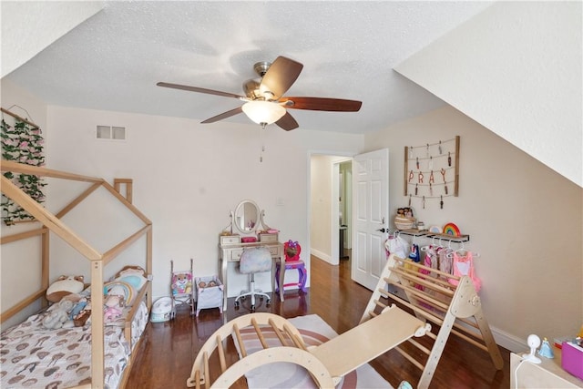 bedroom with wood finished floors, baseboards, visible vents, ceiling fan, and a textured ceiling