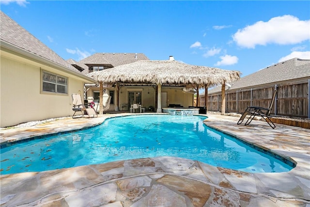 view of swimming pool with a patio, fence, and a pool with connected hot tub