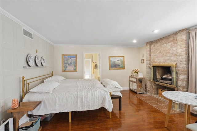 bedroom with visible vents, ornamental molding, wood finished floors, a fireplace, and baseboards