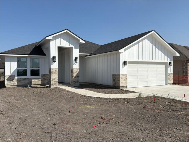 view of front of home featuring driveway, brick siding, board and batten siding, and an attached garage