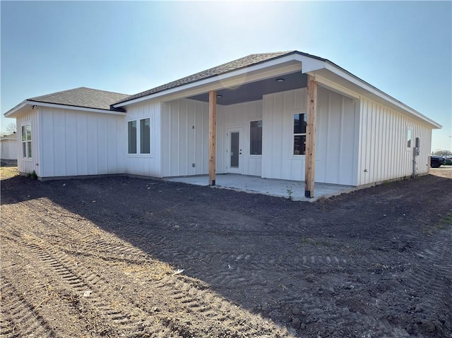 back of property featuring roof with shingles, board and batten siding, and a patio area