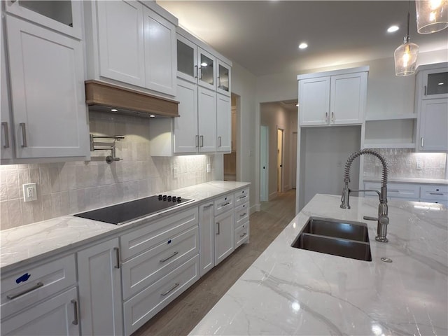 kitchen with white cabinetry, glass insert cabinets, black electric stovetop, and a sink