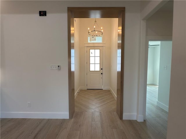 foyer entrance featuring a chandelier, baseboards, and wood finished floors