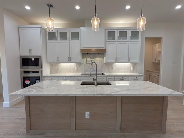 kitchen with visible vents, a sink, appliances with stainless steel finishes, decorative backsplash, and light stone countertops