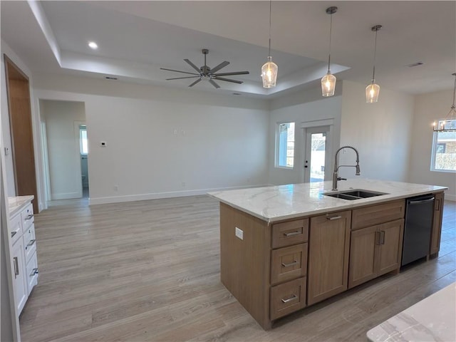 kitchen featuring dishwasher, light wood-style floors, a tray ceiling, and a sink