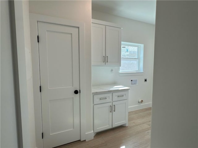 laundry area with electric dryer hookup, washer hookup, light wood-style flooring, cabinet space, and baseboards