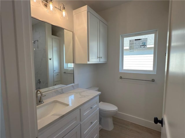 bathroom with baseboards, walk in shower, toilet, wood finished floors, and vanity