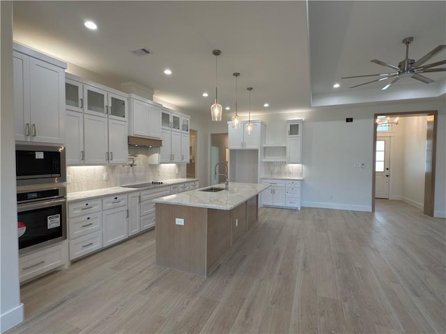 kitchen featuring a sink, light wood finished floors, stainless steel oven, built in microwave, and black electric stovetop