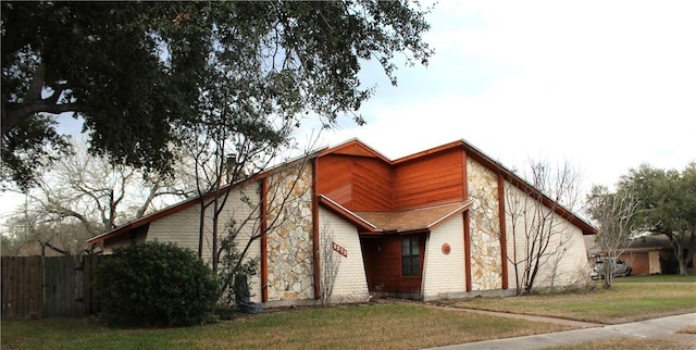 view of front facade with a front yard, brick siding, and fence