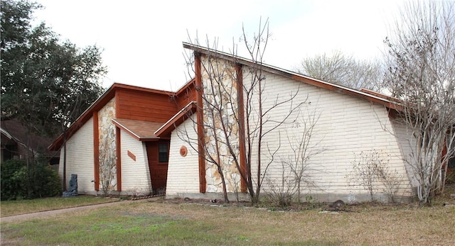 view of home's exterior featuring brick siding and a yard