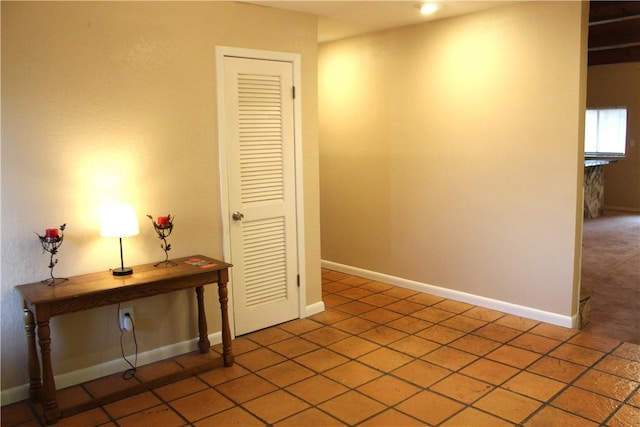 hallway featuring tile patterned floors and baseboards