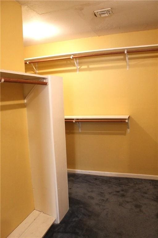 spacious closet featuring dark carpet and visible vents