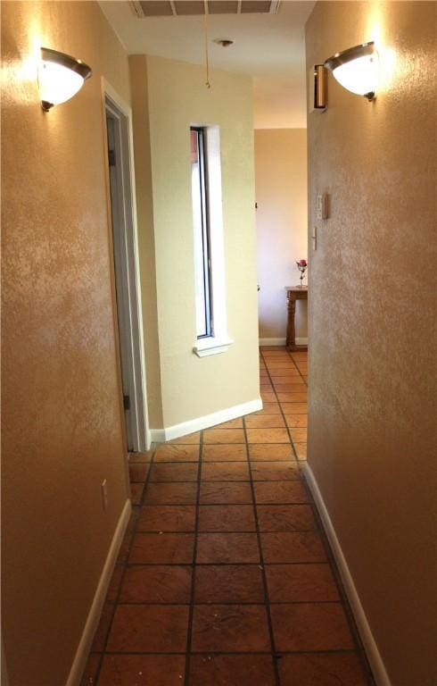 hall with dark tile patterned floors and baseboards