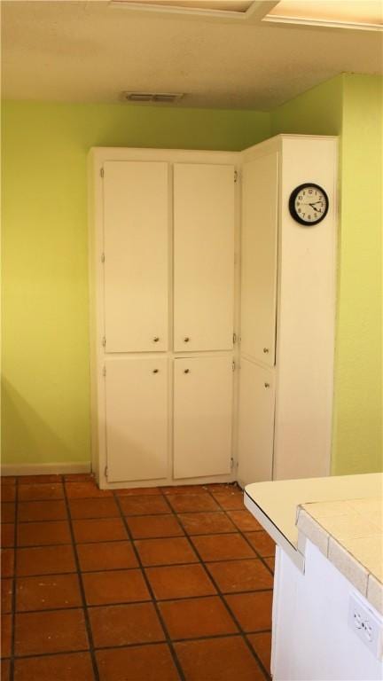 kitchen featuring dark tile patterned floors, visible vents, tile counters, and white cabinets