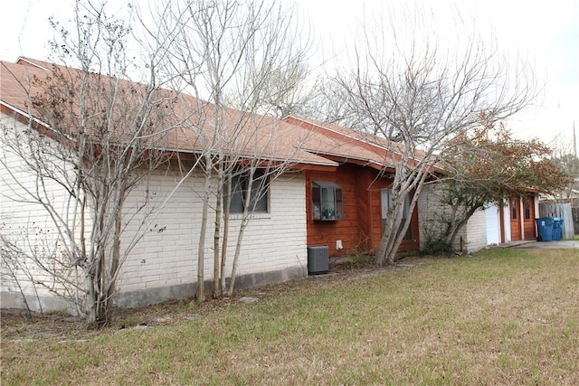 view of home's exterior featuring a yard, central AC, and brick siding