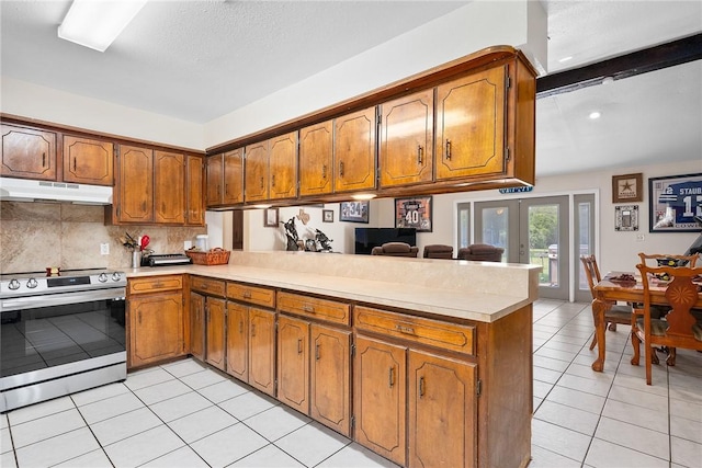 1689 Mooney Ln, Ingleside, TX 78362 - kitchen with stainless steel range with electric stovetop, under cabinet range hood, a peninsula, and brown cabinetry
