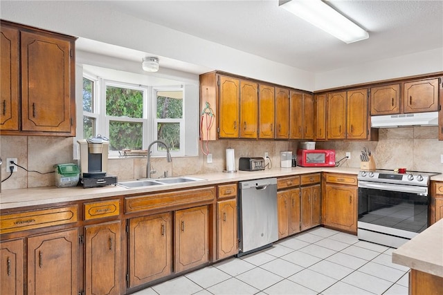 1689 Mooney Ln, Ingleside, TX 78362 - kitchen featuring appliances with stainless steel finishes, under cabinet range hood, brown cabinets, and light countertops