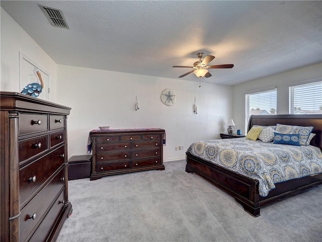 bedroom with light colored carpet, visible vents, ceiling fan, and a textured ceiling