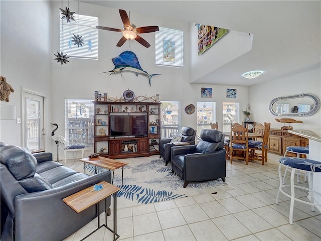 living room with light tile patterned flooring, ceiling fan, and a high ceiling