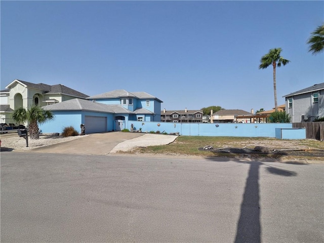 view of front of home with a garage, a residential view, fence, and concrete driveway