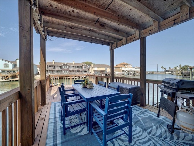 wooden terrace with outdoor dining space, a water view, and a grill