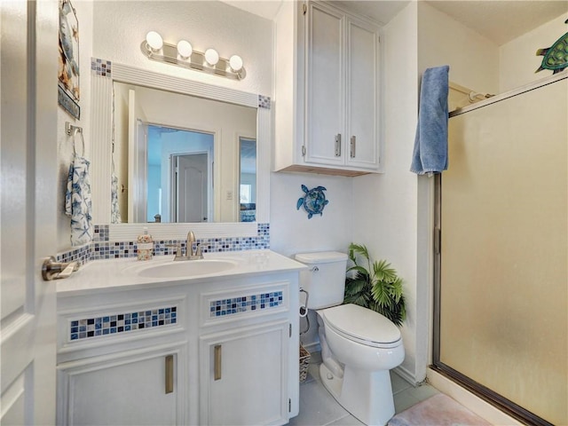 bathroom with backsplash, toilet, vanity, a shower stall, and tile patterned floors