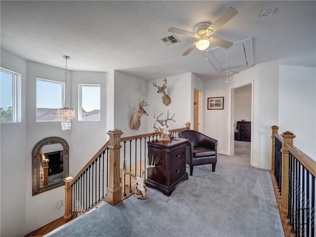 sitting room featuring carpet floors, visible vents, attic access, a textured ceiling, and an upstairs landing