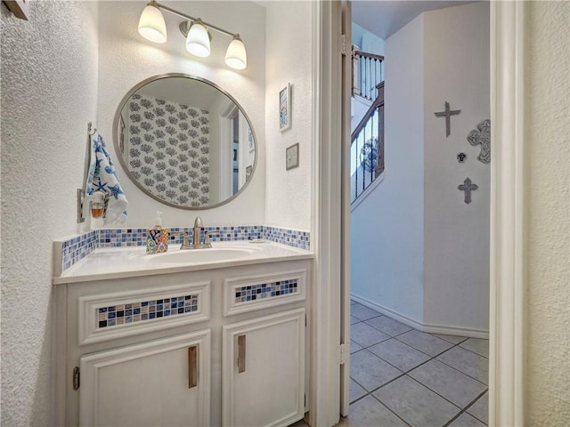 bathroom with a textured wall, vanity, and tile patterned floors