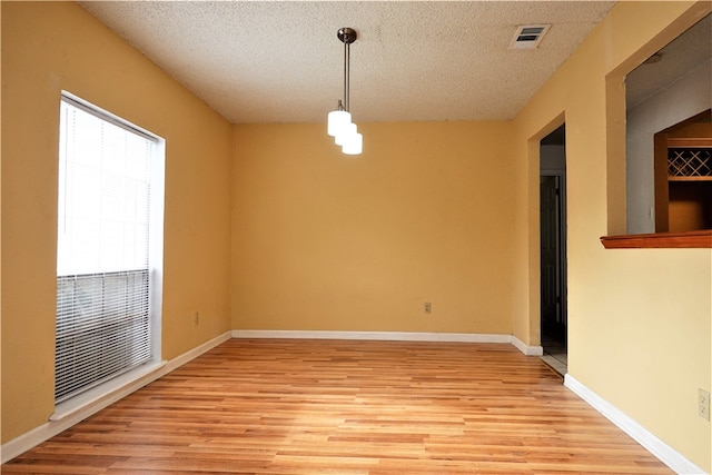 spare room featuring light wood-type flooring and a textured ceiling