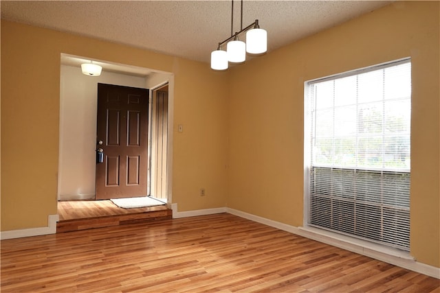 empty room featuring light wood-type flooring and a textured ceiling