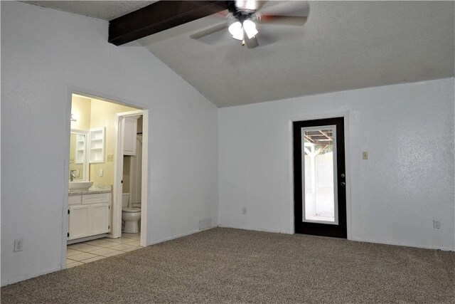 interior space with light carpet, ensuite bath, ceiling fan, sink, and vaulted ceiling with beams