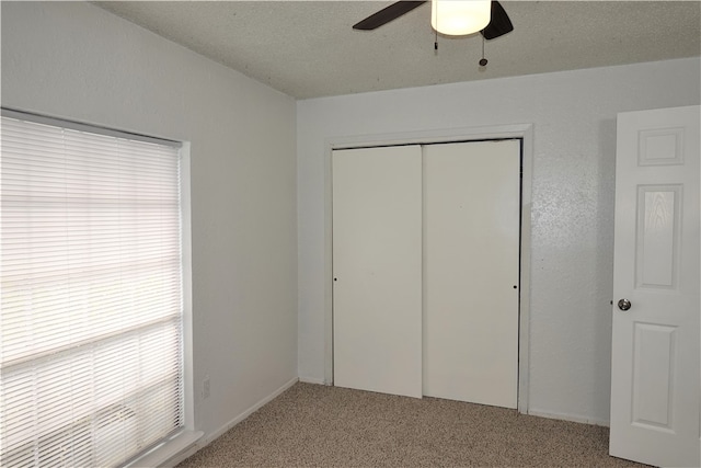 unfurnished bedroom with ceiling fan, a closet, carpet floors, and a textured ceiling