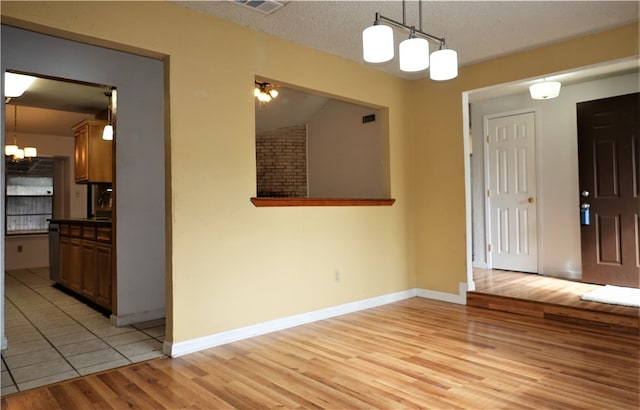 foyer entrance featuring a chandelier, light hardwood / wood-style floors, and a textured ceiling