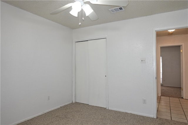 unfurnished bedroom featuring carpet flooring, ceiling fan, a closet, and a textured ceiling