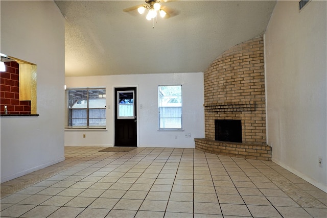 unfurnished living room featuring ceiling fan, a brick fireplace, a textured ceiling, vaulted ceiling, and light tile patterned floors