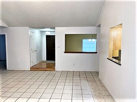 tiled spare room with a textured ceiling and vaulted ceiling