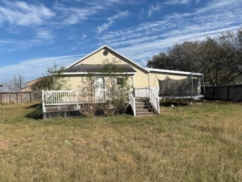 604 N Ironwood Ave, Bishop, TX 78343 - rear view of house featuring fence, a trampoline, a deck, and a yard