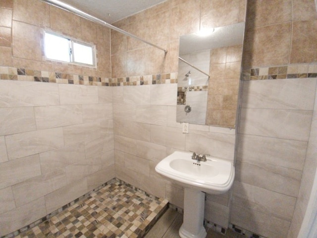 bathroom featuring a tile shower and tile walls