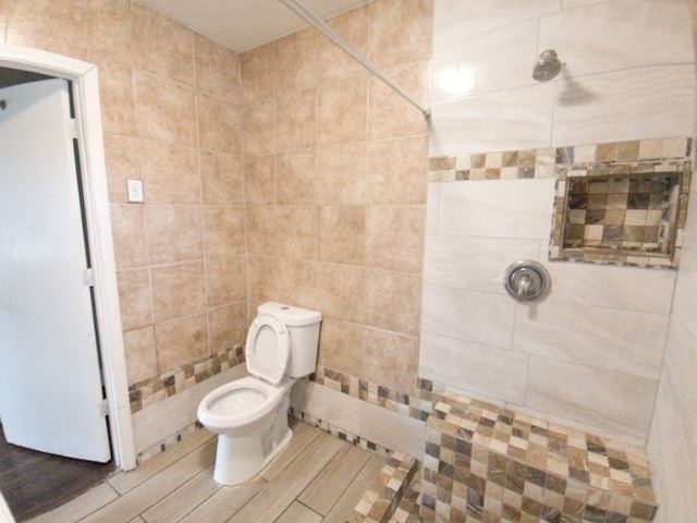 bathroom featuring toilet, tile walls, and a tile shower