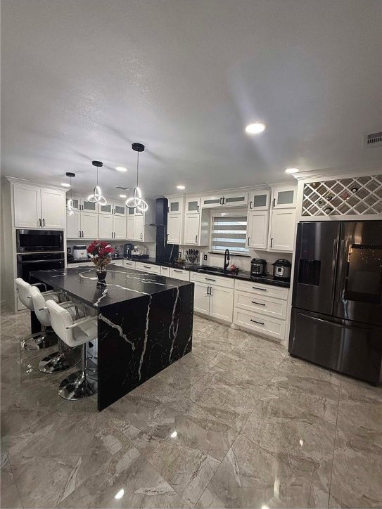 kitchen featuring black appliances, a center island, a kitchen bar, and hanging light fixtures