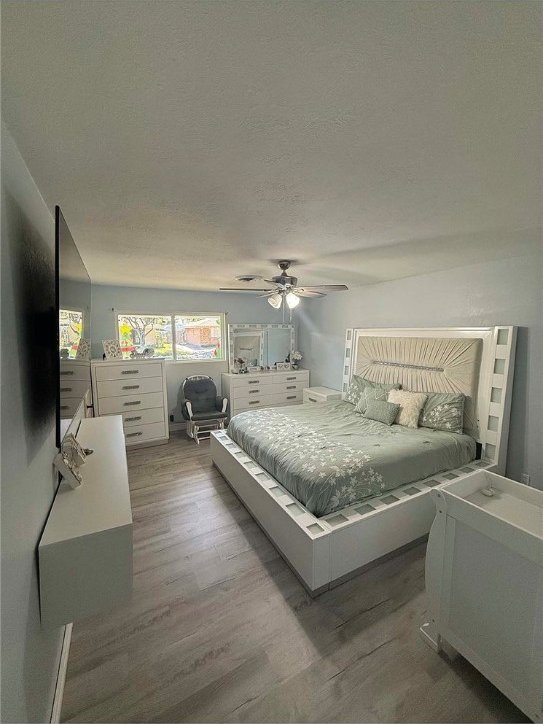 bedroom with ceiling fan, a textured ceiling, and hardwood / wood-style flooring