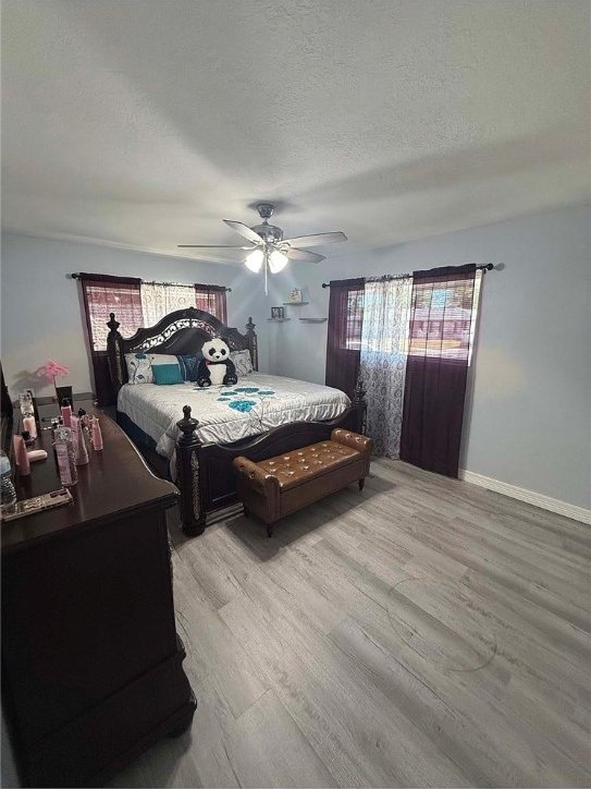 bedroom with a textured ceiling, light wood-type flooring, and ceiling fan