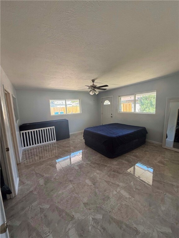 unfurnished bedroom featuring a textured ceiling, multiple windows, and ceiling fan