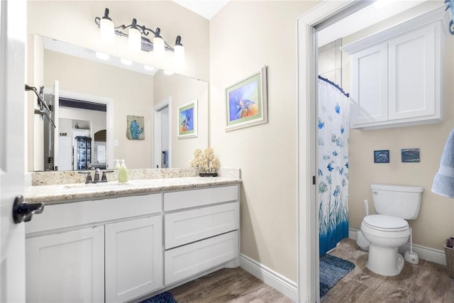 full bath with toilet, a shower with shower curtain, wood finished floors, vanity, and baseboards